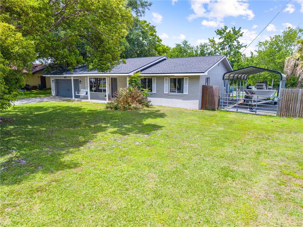 A single-story gray brick house with a dark roof, front porch, and a boat carport — 6137 BASS HIGHWAY, ST CLOUD, FL