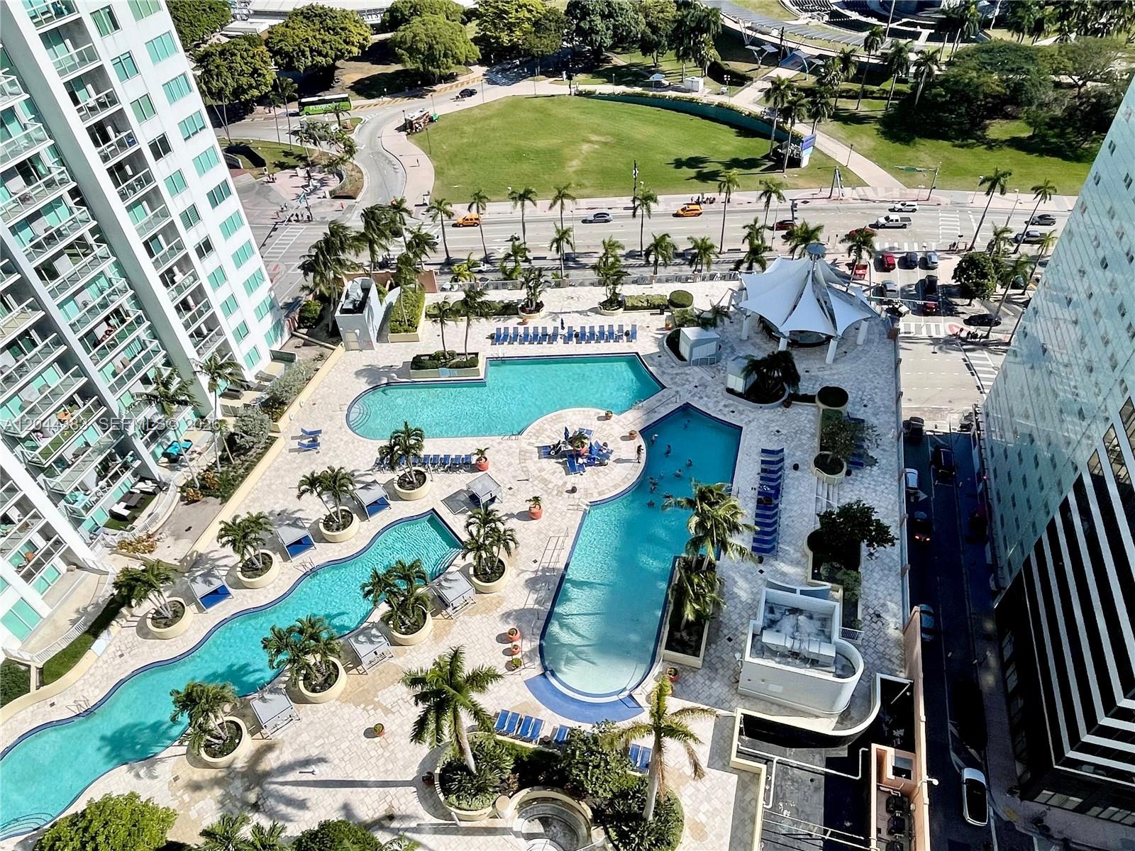 An aerial view shows a large swimming pool complex with lounge chairs and palm trees — 253 NE 2nd St # 2409, Miami FL 33132, MIAMI, FL