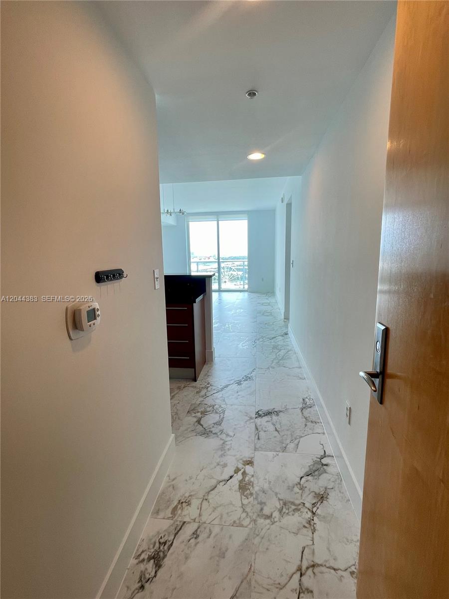A hallway with white marble-patterned tile flooring leads toward a bright living area — 253 NE 2nd St # 2409, Miami FL 33132, MIAMI, FL