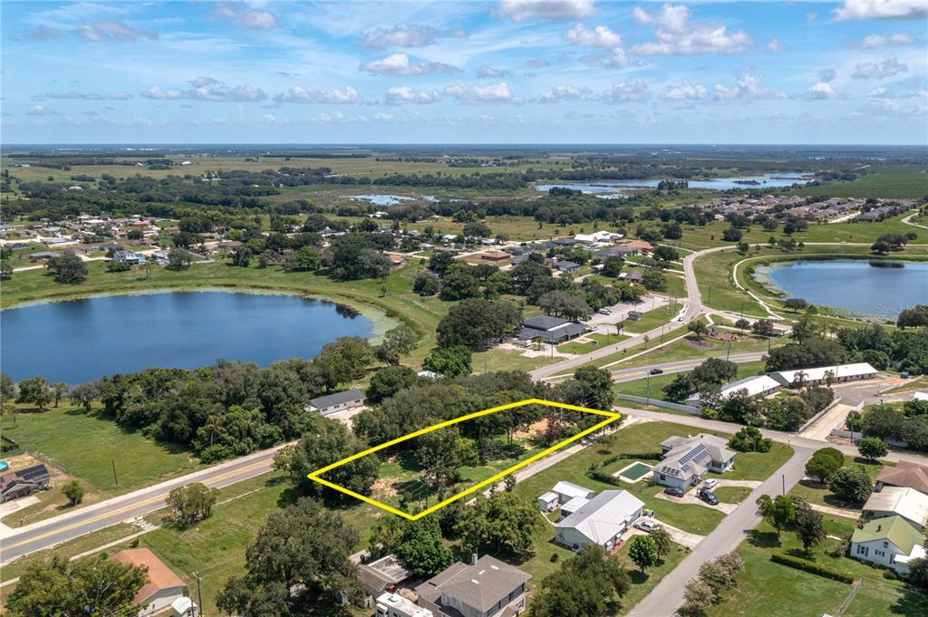 An aerial view shows a vacant, rectangular lot outlined in yellow near a lake — 504 E MAIN STREET, DUNDEE, FL