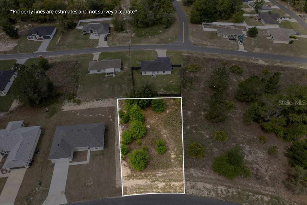 An aerial view shows a vacant, rectangular residential lot surrounded by existing houses and vegetation — SW 58 TER, OCALA, FL