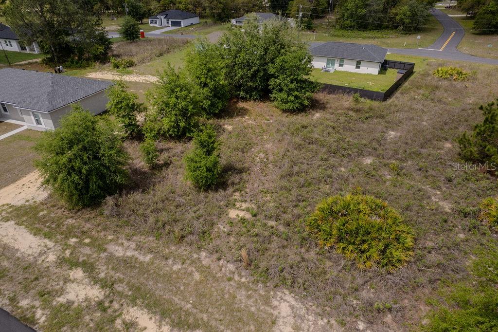 An aerial view shows a vacant, grassy lot with several trees and surrounding residential homes — SW 58 TER, OCALA, FL