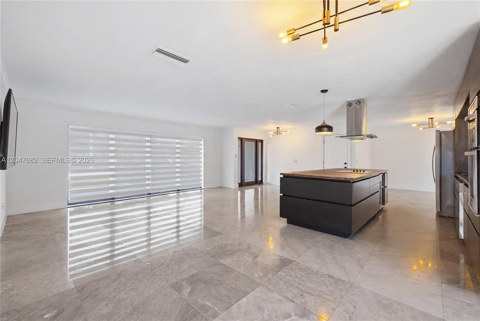 A modern kitchen features a dark island, stainless steel appliances, and large gray floor tiles — BOCA RATON, FL