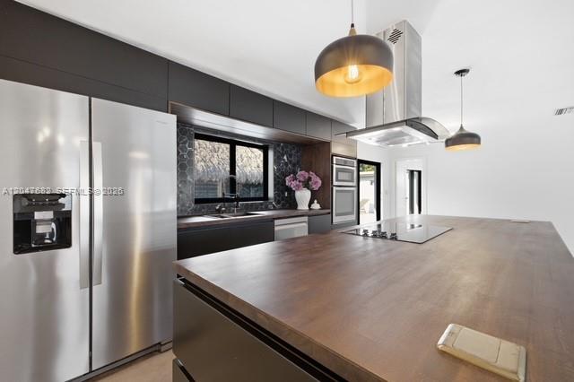 A modern kitchen features a large wooden island, stainless steel appliances, and dark cabinetry — BOCA RATON, FL