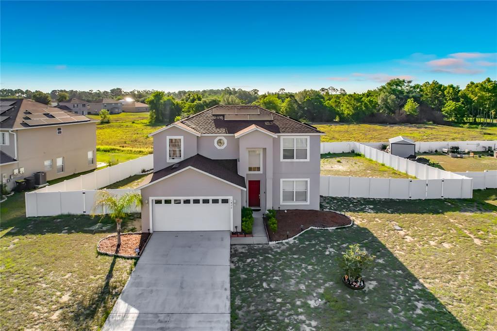 An aerial view of a two-story suburban house with a white garage and fenced yard — 1425 NELSON BROOK WAY, KISSIMMEE, FL