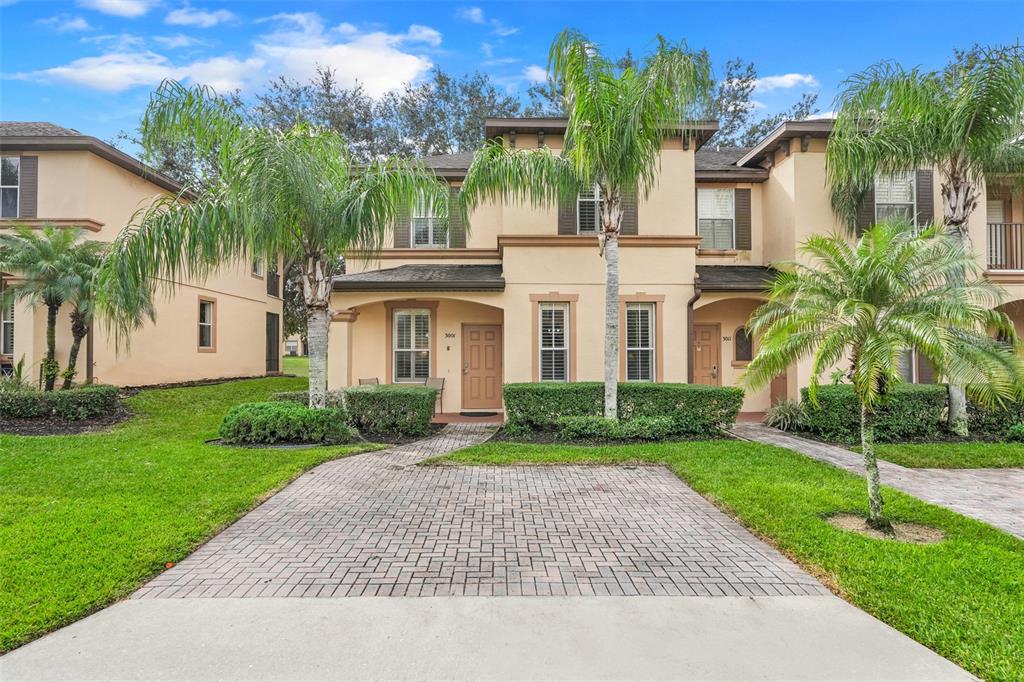 A two-story tan stucco townhouse with a paved driveway and palm trees in the front — 3001 CALABRIA AVENUE, DAVENPORT, FL