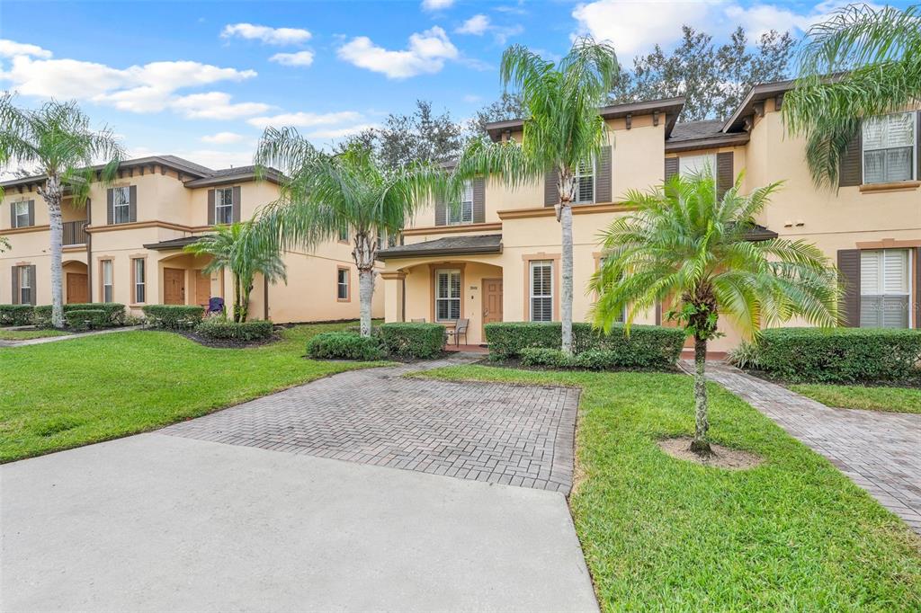 A multi-story tan townhouse complex features a paved driveway, green lawn, and several palm trees — 3001 CALABRIA AVENUE, DAVENPORT, FL