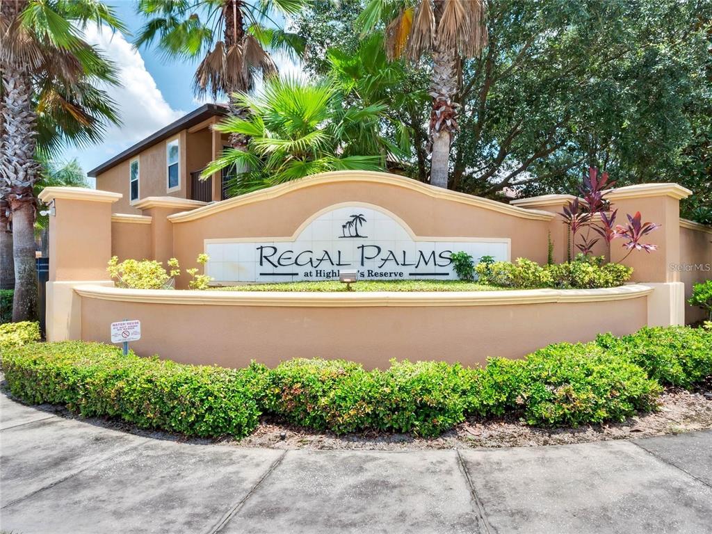 A tan stucco monument sign for Regal Palms at Highlands Reserve sits behind green landscaping — 3001 CALABRIA AVENUE, DAVENPORT, FL
