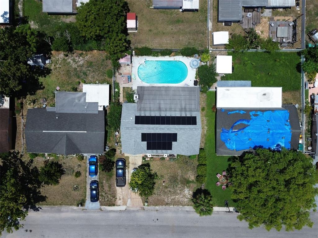 An aerial view shows three residential properties, including one with a swimming pool and solar panels — 10825 BRIDLETON ROAD, PORT RICHEY, FL