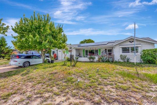A single-story white house with solar panels on the roof and a parked white car — 10825 BRIDLETON ROAD, PORT RICHEY, FL