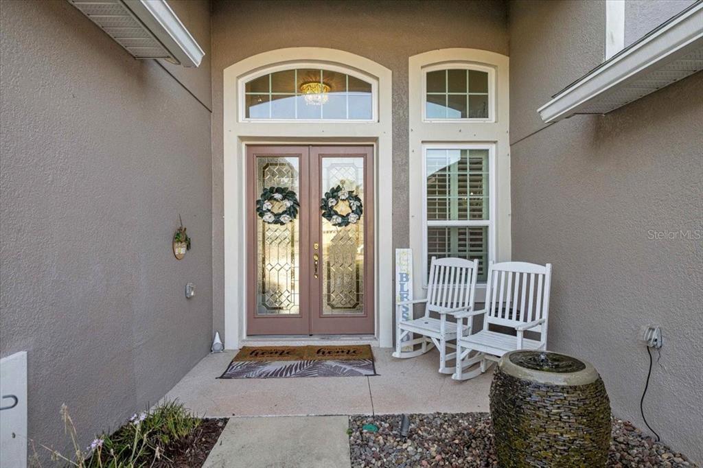 A front entryway features double glass doors, two white rocking chairs, and a stone fountain — 9095 LAUREL RIDGE DRIVE, MOUNT DORA, FL