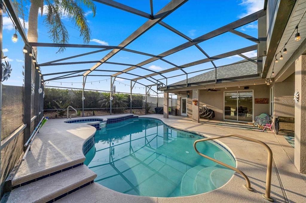 A screened-in swimming pool and spa with a concrete deck under a covered patio — 9095 LAUREL RIDGE DRIVE, MOUNT DORA, FL