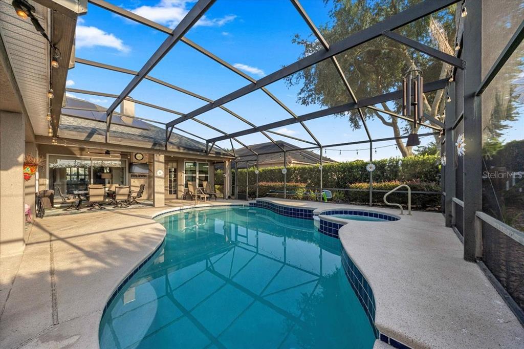 A screened-in patio features a swimming pool, a small attached spa, and outdoor furniture — 9095 LAUREL RIDGE DRIVE, MOUNT DORA, FL