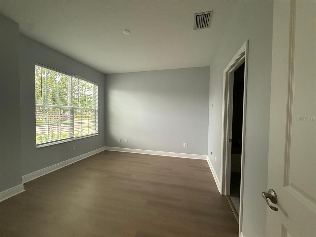An empty bedroom features light blue walls, wood-look flooring, and a window with blinds — 34128 EVERGREEN HILL COURT, WESLEY CHAPEL, FL