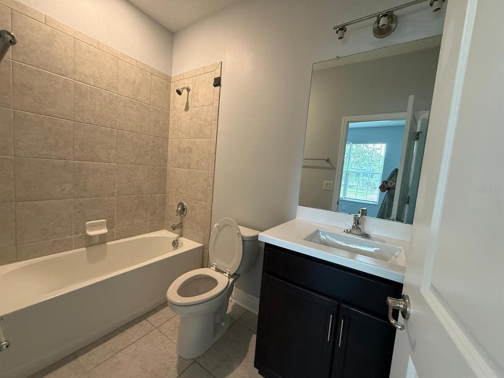 A bathroom features a dark vanity, a toilet, and a bathtub with tiled walls — 34128 EVERGREEN HILL COURT, WESLEY CHAPEL, FL