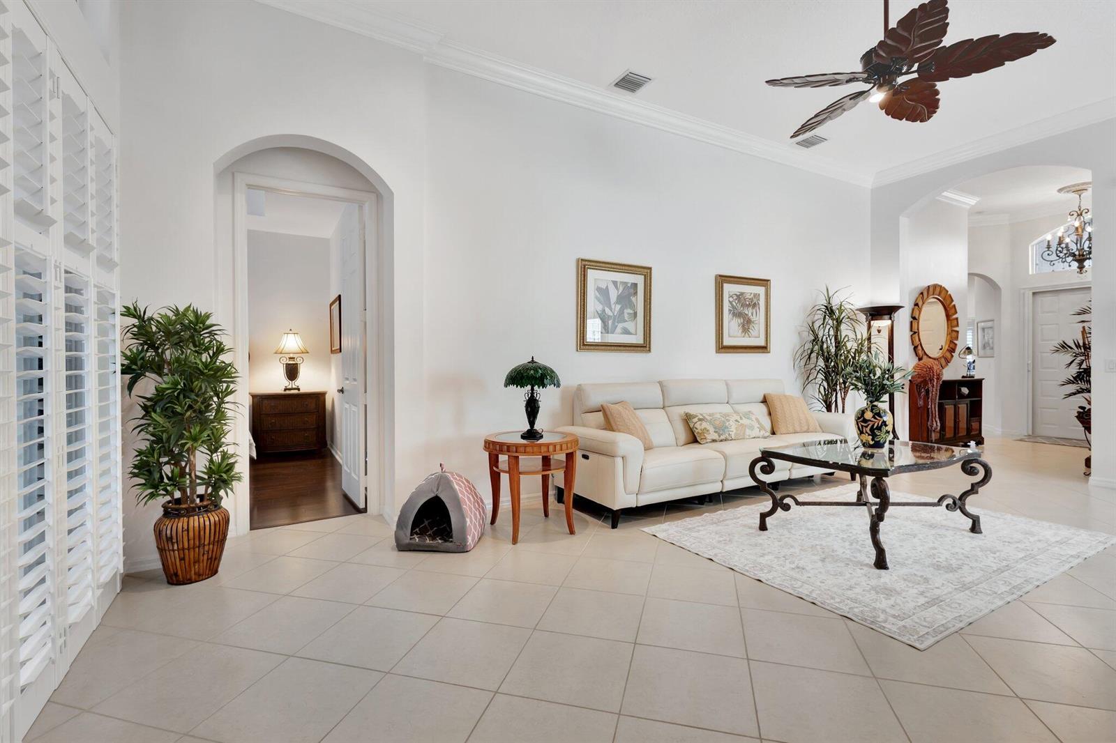 A bright living room features white walls, tile flooring, a white sofa, and a ceiling fan — 10732 Grande Boulevard, West Palm Beach FL 33412, WEST PALM BEACH, FL