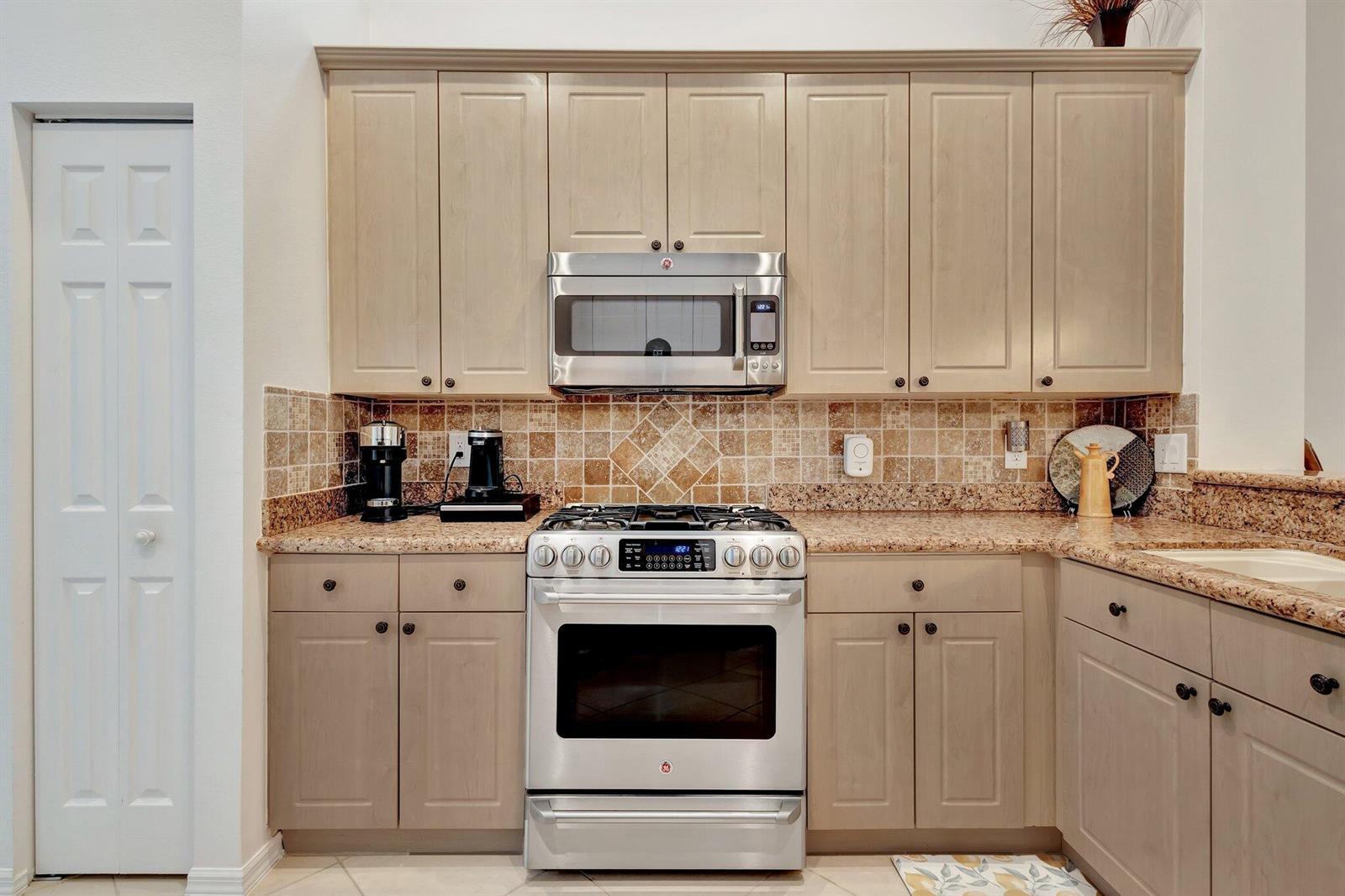 A kitchen with light wood cabinets, stainless steel appliances, and a tan granite countertop — 10732 Grande Boulevard, West Palm Beach FL 33412, WEST PALM BEACH, FL