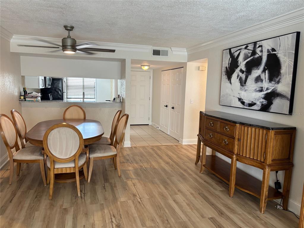 A dining room features a wooden table with chairs, a sideboard, and light wood flooring — 121 ISLAND WAY UNIT 331, CLEARWATER BEACH, FL