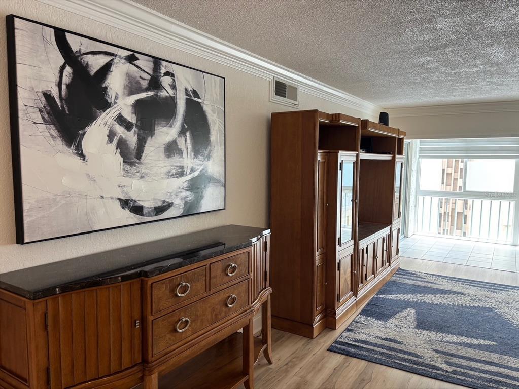 A living room features a wooden media console, a matching sideboard, and abstract wall art — 121 ISLAND WAY UNIT 331, CLEARWATER BEACH, FL