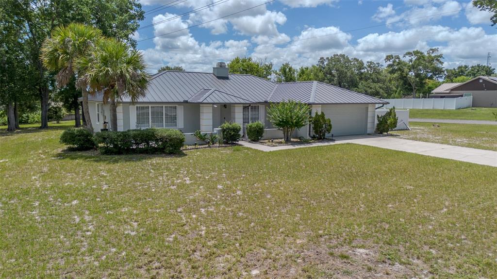 A single-story house with a metal roof, light-colored siding, and a concrete driveway — 1861 CROWLEY CIRCLE E, LONGWOOD, FL