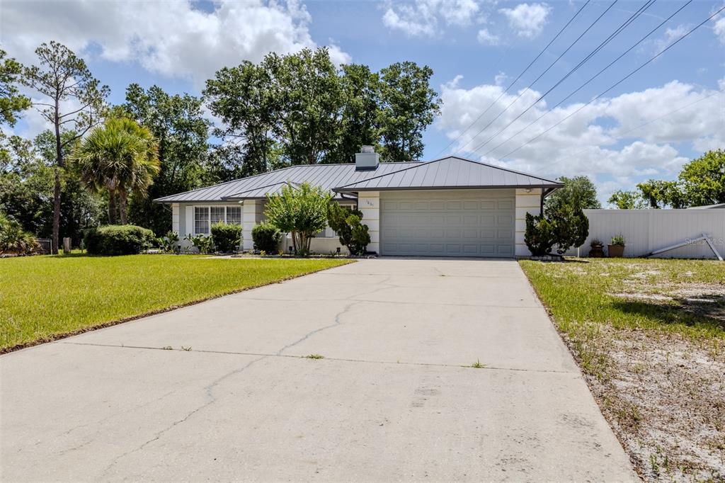 A single-story house with a metal roof, a two-car garage, and a concrete driveway — 1861 CROWLEY CIRCLE E, LONGWOOD, FL