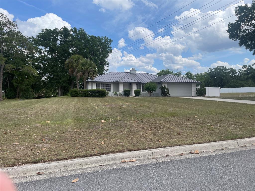 A single-story house with a metal roof and a two-car garage sits on a lawn — 1861 CROWLEY CIRCLE E, LONGWOOD, FL