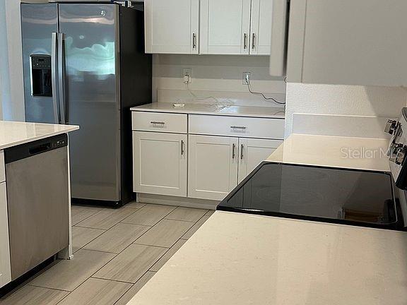 A kitchen features white cabinets, stainless steel appliances, and light-colored countertops — 2505 VICTORIOUS FALLS AVENUE, PLANT CITY, FL