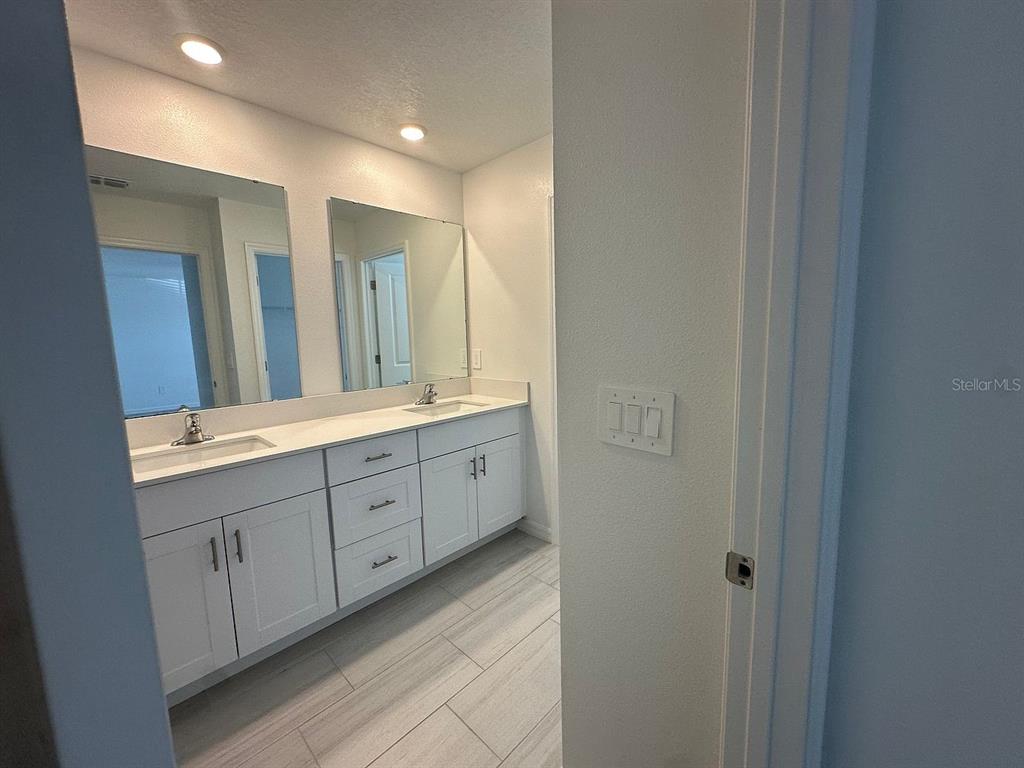 A bathroom features a double vanity with white cabinets, light countertops, and two wall mirrors — 2505 VICTORIOUS FALLS AVENUE, PLANT CITY, FL