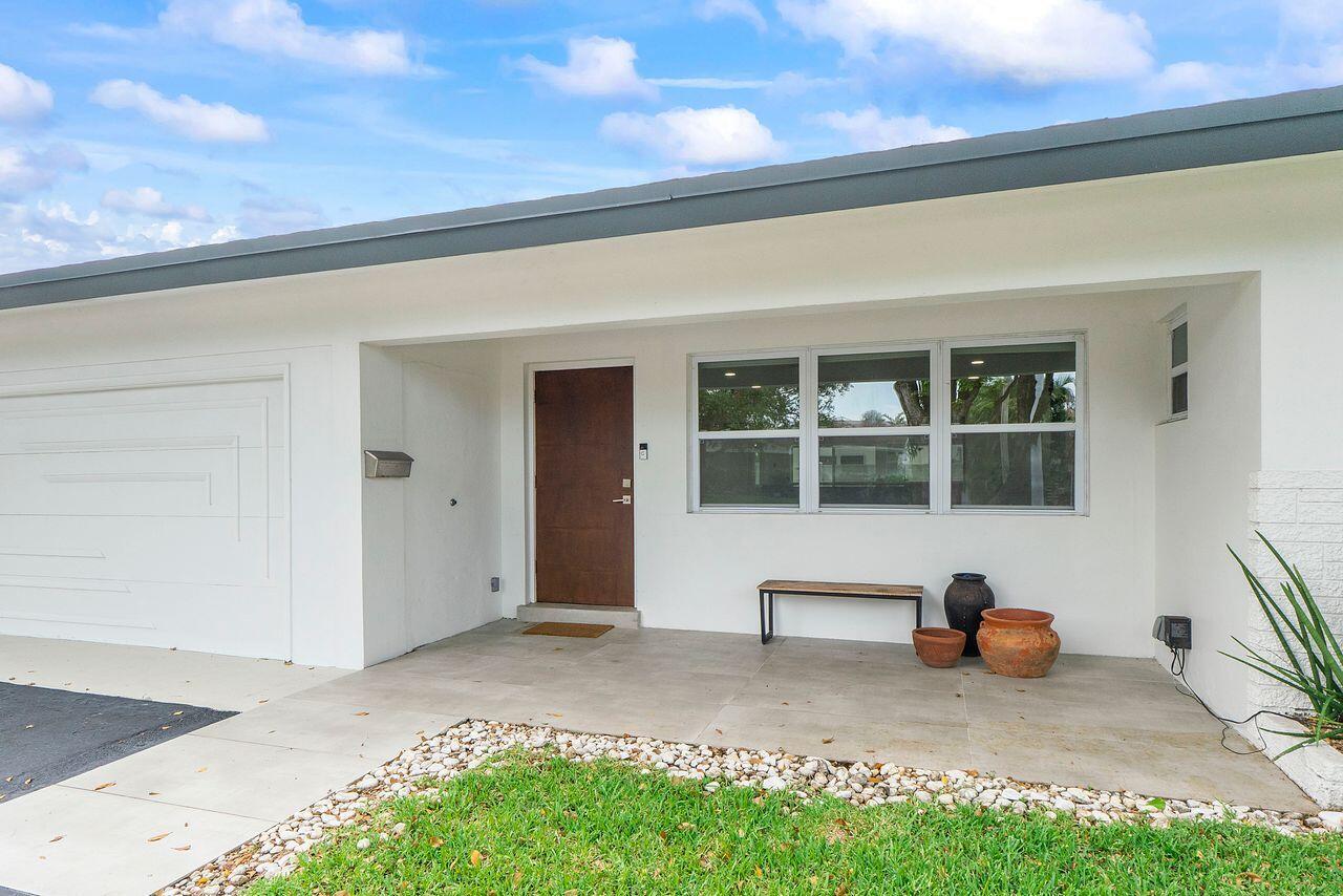 A white house exterior features a brown front door, large windows, and a tiled porch — 701 SE 5th Court, Pompano Beach FL 33060, POMPANO BEACH, FL