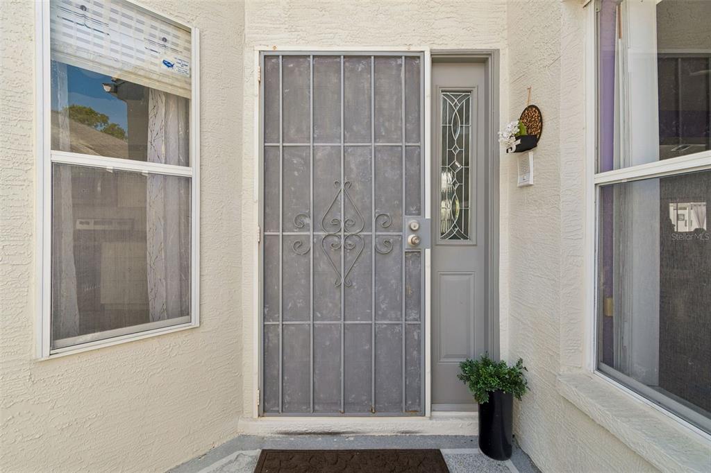 A front entryway features a gray security screen door, a sidelight, and two windows — 10491 CASA GRANDE CIRCLE, SPRING HILL, FL