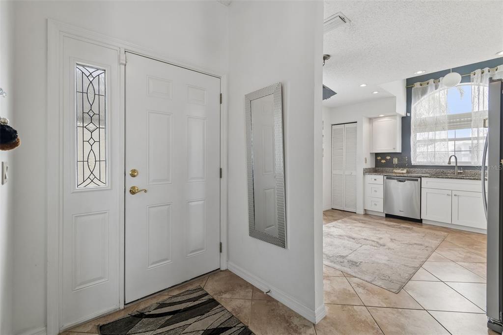 An entryway with a white front door leads into a kitchen with white cabinets — 10491 CASA GRANDE CIRCLE, SPRING HILL, FL