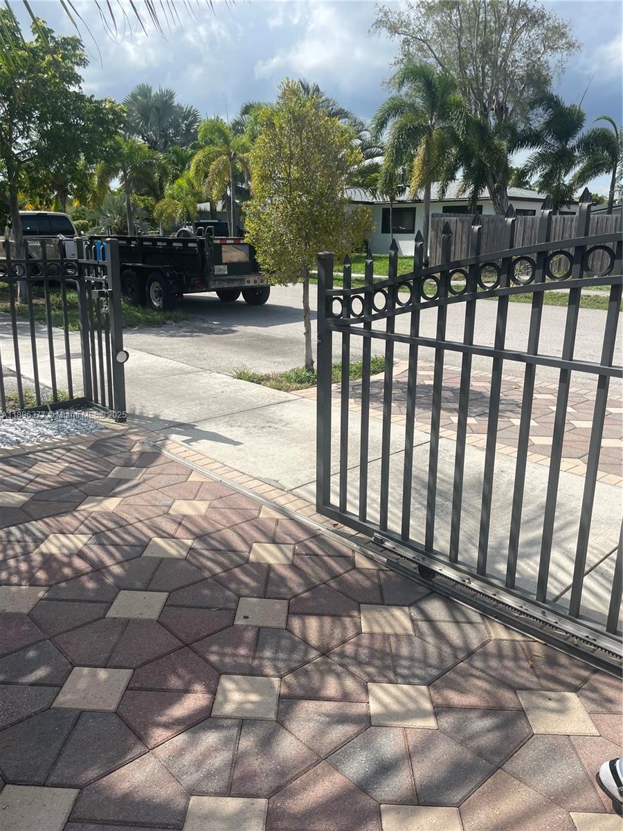 A metal gate opens onto a paved driveway with a trailer parked in the background — 240 NE 27th St # 1, Pompano Beach FL 33064, POMPANO BEACH, FL