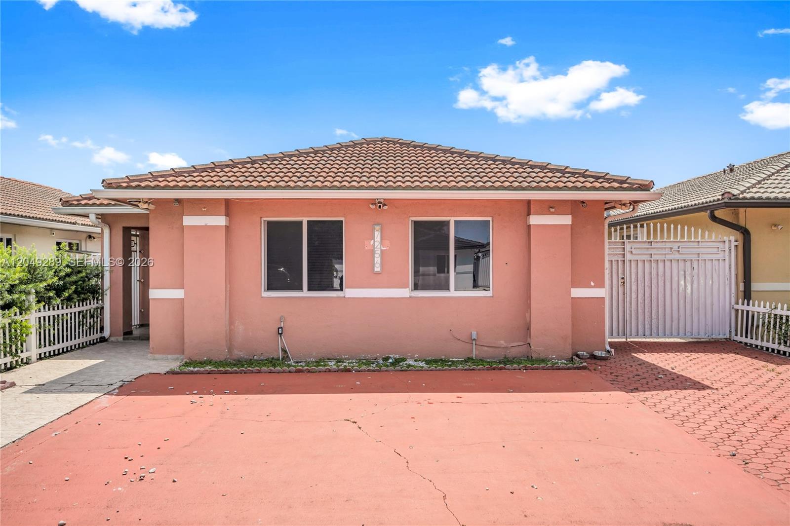 The exterior of a single-story pink house features a tiled roof and a paved driveway — 7256 W 34th Ln, Hialeah FL 33018, HIALEAH, FL