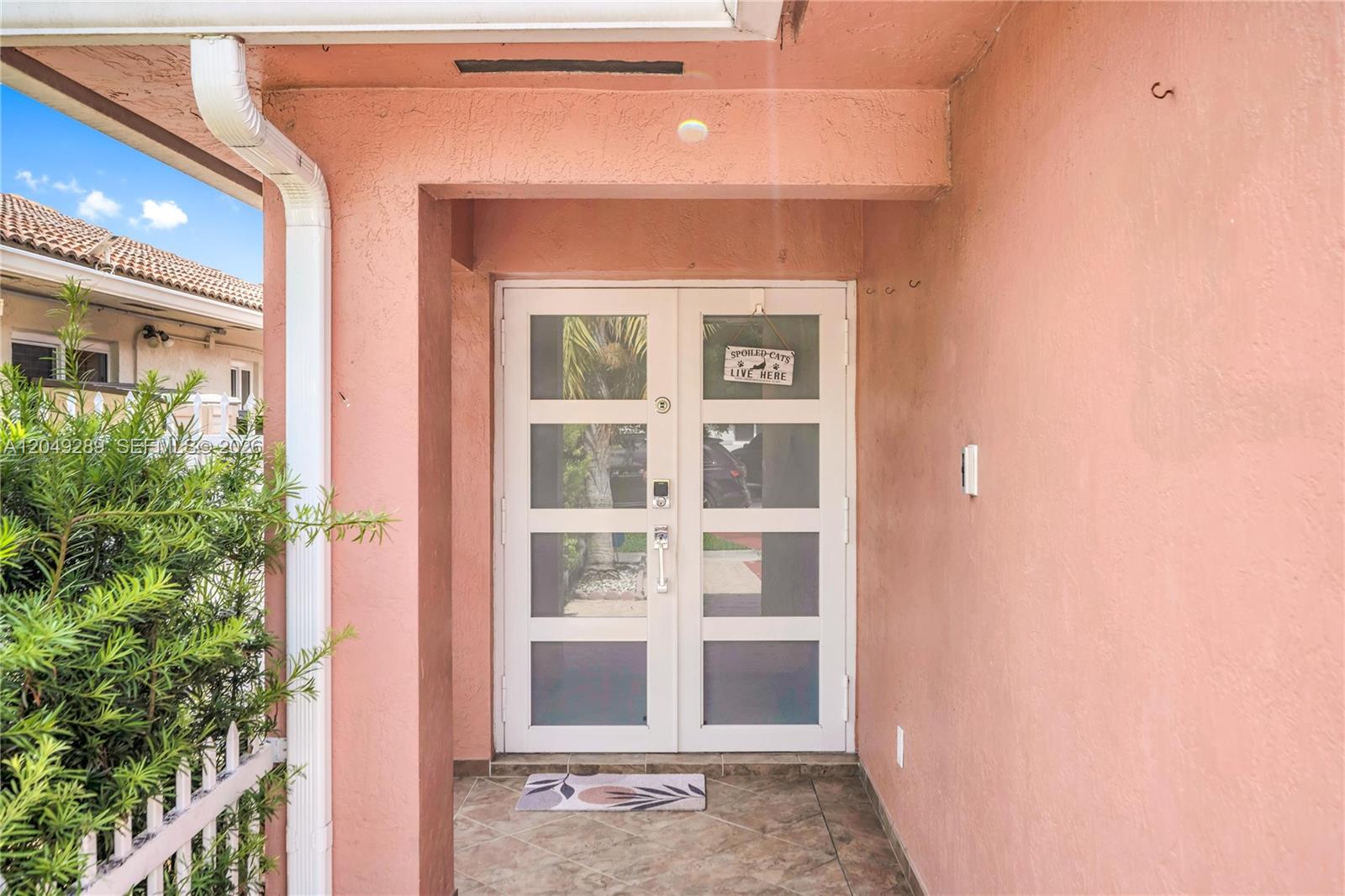 A pink stucco exterior features a white double door with glass panels and a sign — 7256 W 34th Ln, Hialeah FL 33018, HIALEAH, FL