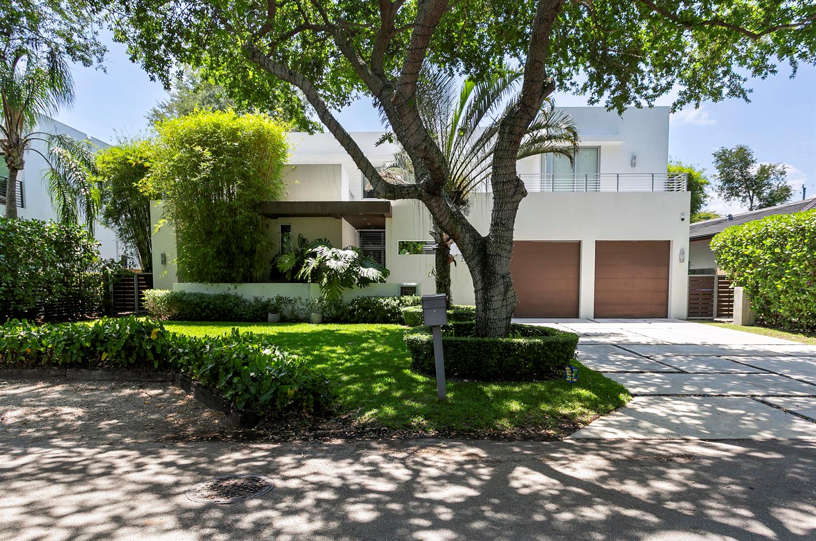 A modern two-story white house features a large tree, a manicured lawn, and two garages — 7700 SW 53rd Court, Miami FL 33143, MIAMI, FL