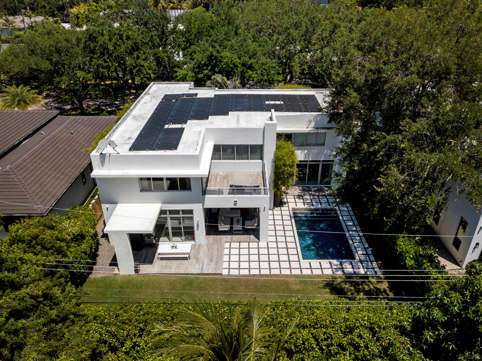 An aerial view of a modern white house with a flat roof, solar panels, and pool — 7700 SW 53rd Court, Miami FL 33143, MIAMI, FL