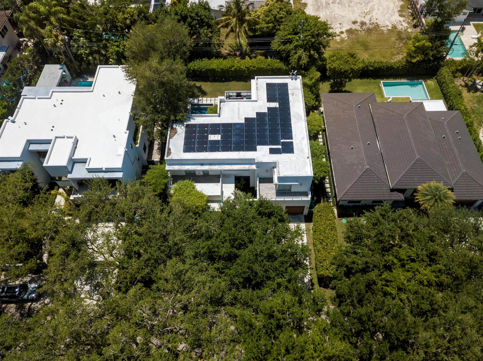 An aerial view shows three houses with pools, including one with a rooftop solar array — 7700 SW 53rd Court, Miami FL 33143, MIAMI, FL