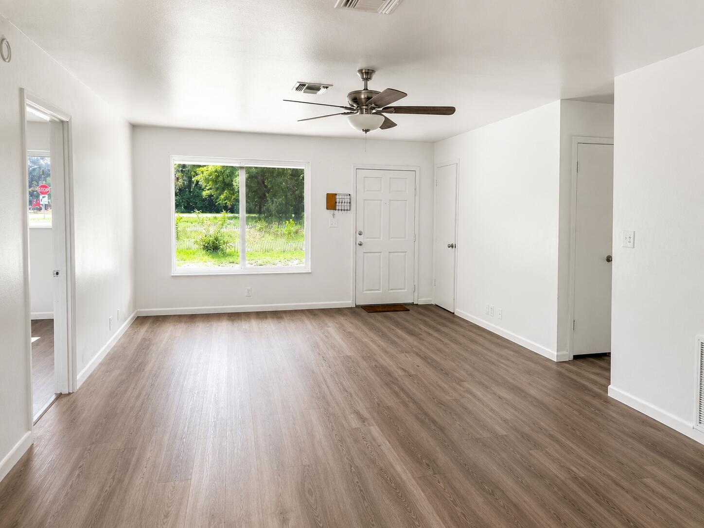 An empty room with white walls, wood-look flooring, a ceiling fan, and a large window — 8012 U.s. 1, Vero Beach FL 32967, VERO BEACH, FL