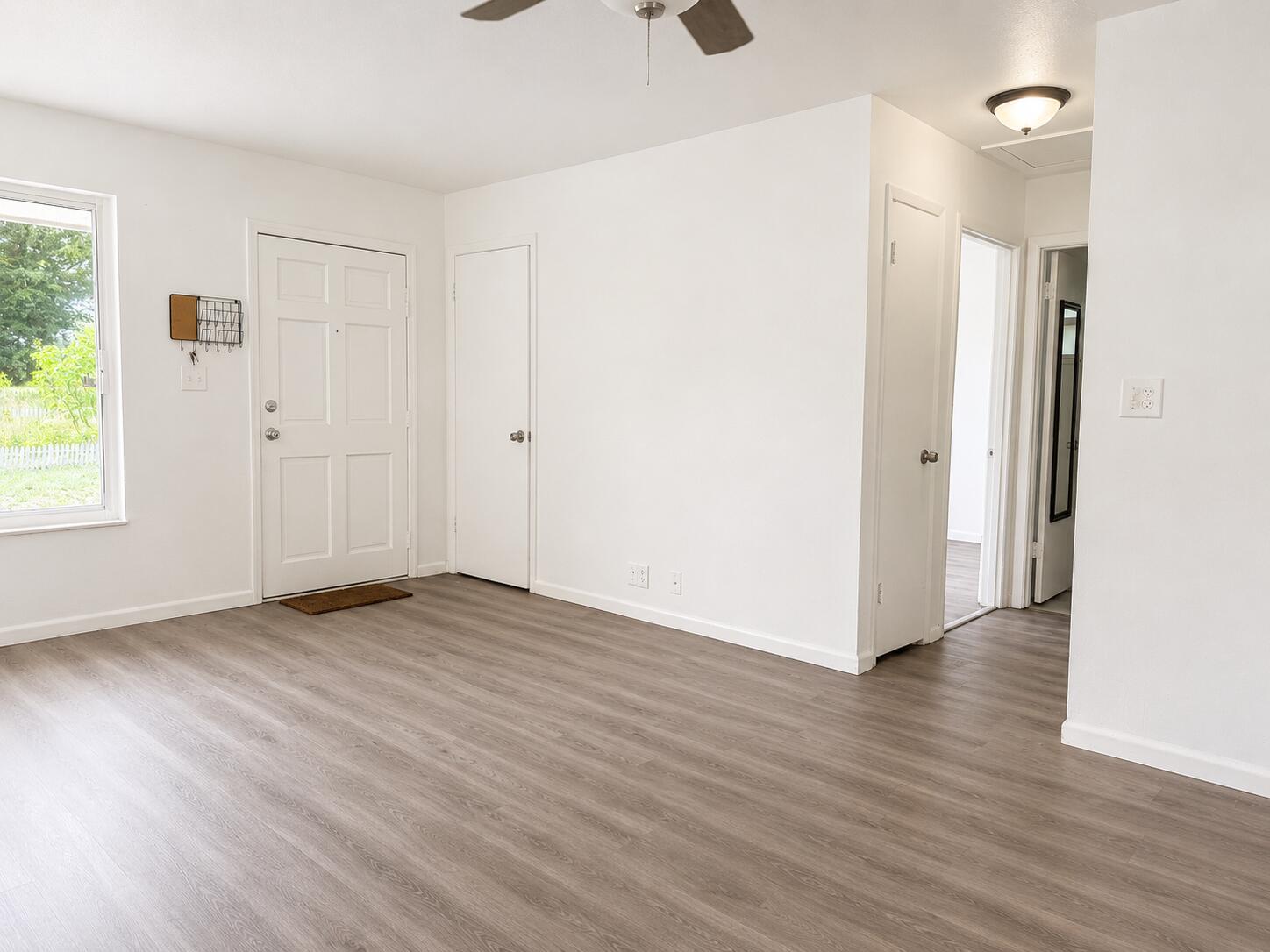 An empty room with white walls, wood-look flooring, a front door, and multiple interior doors — 8012 U.s. 1, Vero Beach FL 32967, VERO BEACH, FL