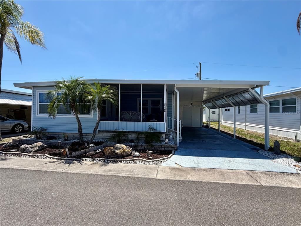 A light blue manufactured home features a screened front porch and an attached carport — 34540 VIOLET DRIVE N, PINELLAS PARK, FL