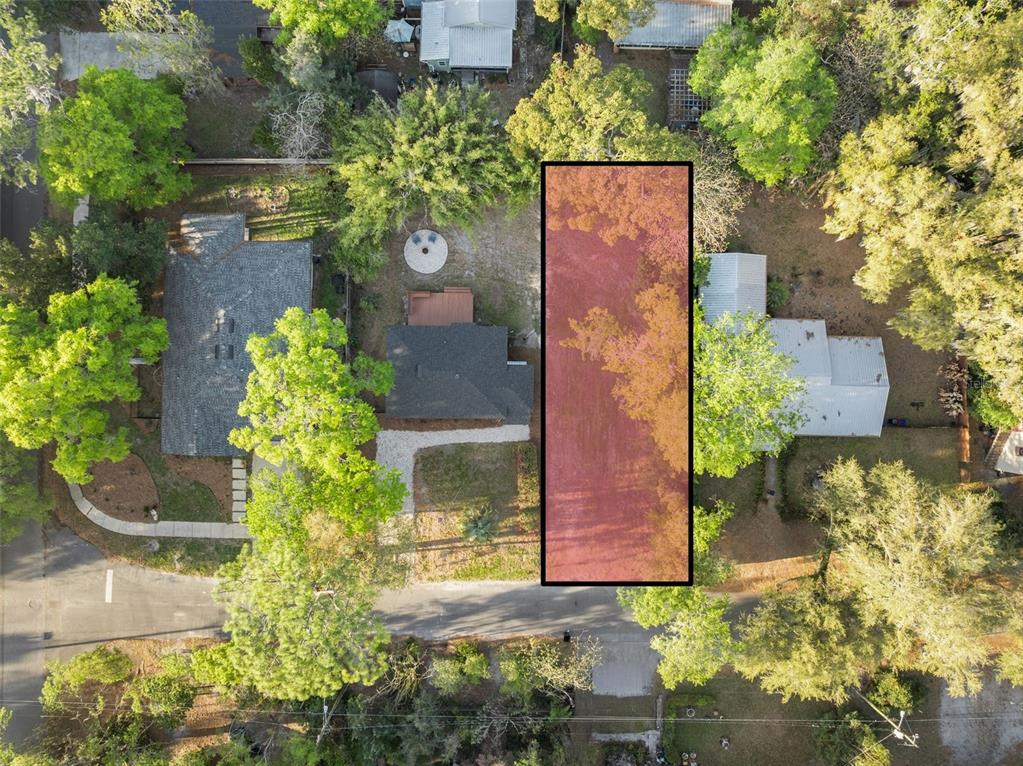 An aerial view shows a rectangular vacant lot highlighted in red between two residential houses — NE 7TH PLACE, GAINESVILLE, FL