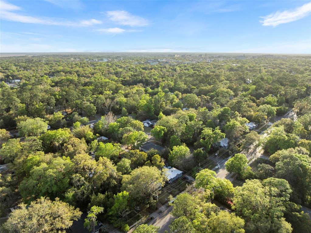 An aerial view shows a residential neighborhood densely covered with trees and scattered houses — NE 7TH PLACE, GAINESVILLE, FL
