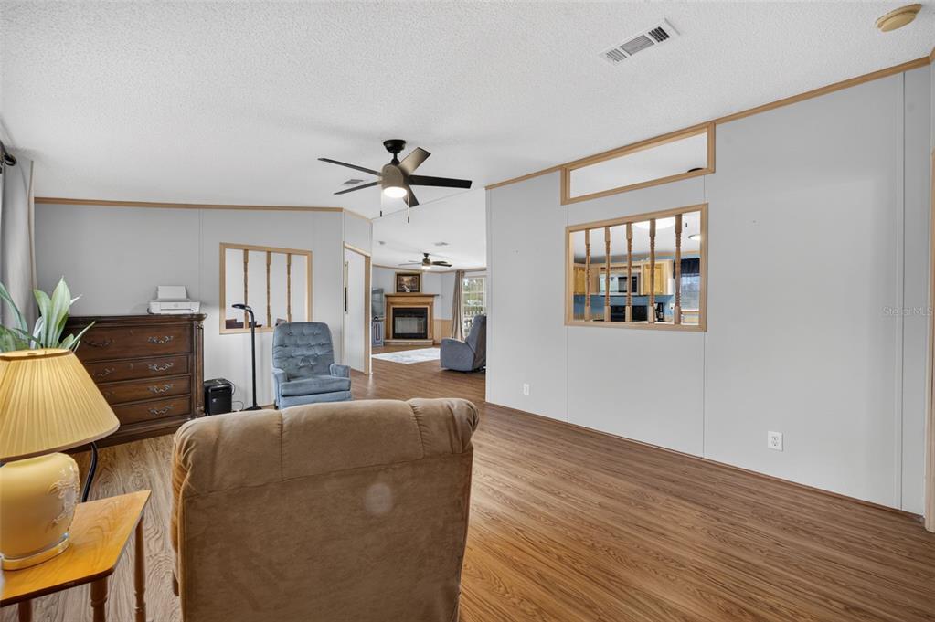 A living room with light gray walls, wood-look flooring, and a partial wall with spindles — 11416 PHEASANT TRAIL, LEESBURG, FL