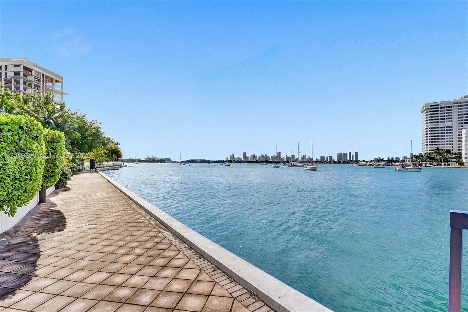 A paved walkway runs alongside a waterfront with boats and a distant city skyline — 1430 16th St # 1, Miami Beach FL 33139, MIAMI BEACH, FL