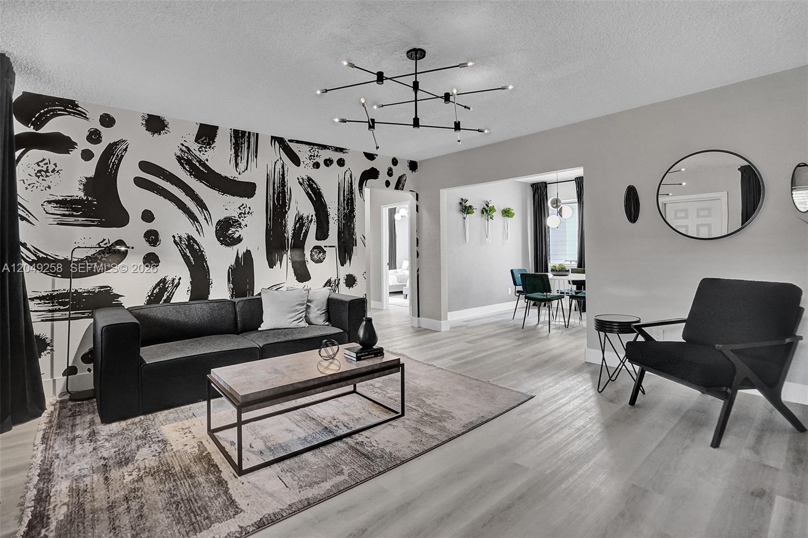 A living room features a bold black-and-white abstract wallpaper, modern furniture, and light wood flooring — 1430 16th St # 1, Miami Beach FL 33139, MIAMI BEACH, FL