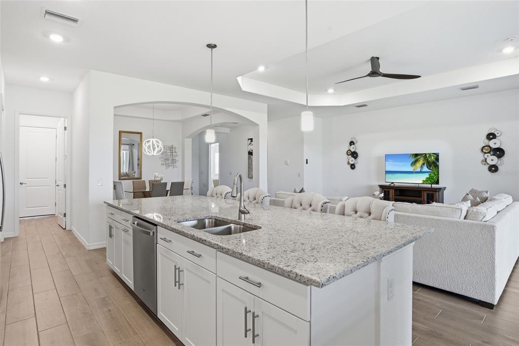A kitchen island with granite countertops and white cabinets overlooks an open-concept living area — 14413 HERITAGE LANDING BOULEVARD, PUNTA GORDA, FL