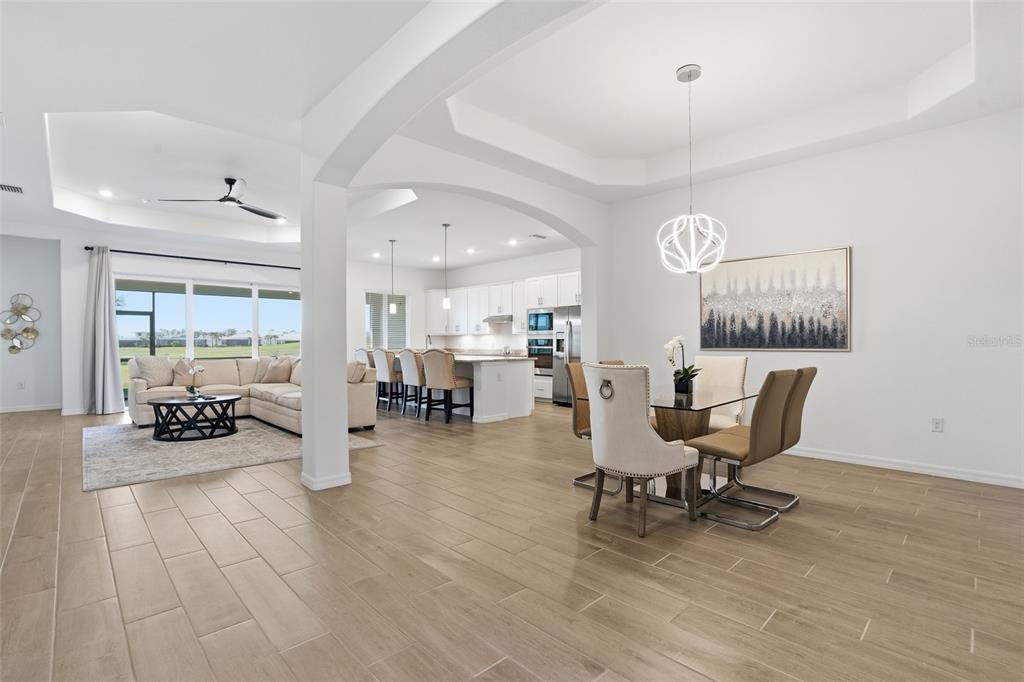 An open-concept living and dining area features light wood-look tile flooring and white cabinetry — 14413 HERITAGE LANDING BOULEVARD, PUNTA GORDA, FL