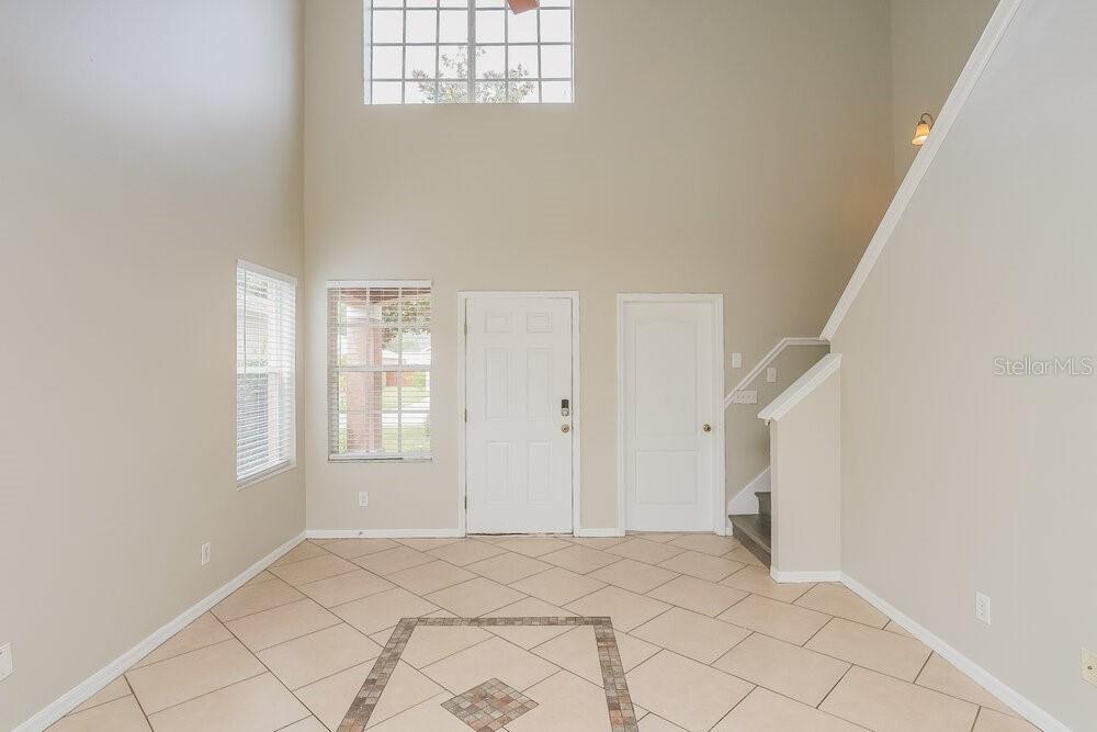 An entryway with high ceilings, tile flooring, a front door, and a staircase — 12723 ADVENTURE DRIVE, RIVERVIEW, FL