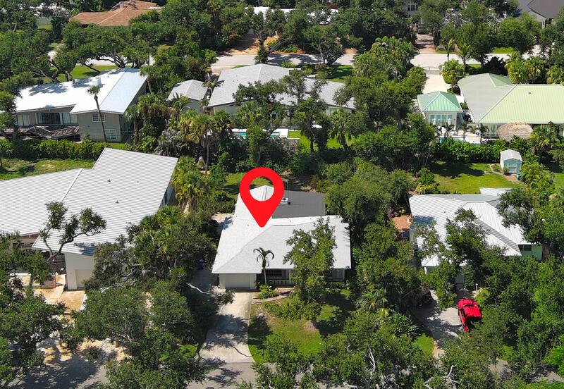 An aerial view shows a residential house with a white roof and a red pin — VERO BEACH, FL
