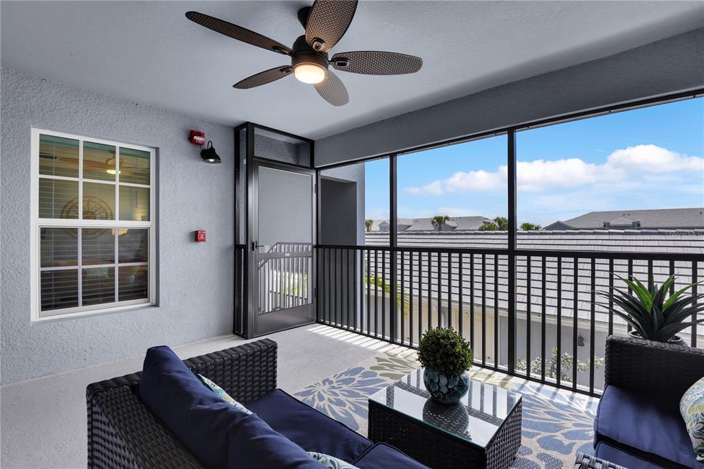A screened-in balcony features wicker furniture, a ceiling fan, and a view of neighboring rooftops — 14271 HERITAGE LANDING BOULEVARD UNIT 1527, PUNTA GORDA, FL